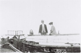 photo: man and woman standing on boat wreck. boat name illalong